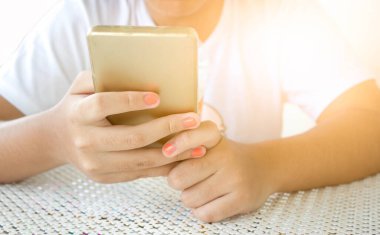 Akıllı telefon kullanan ve süt içen Asyalı kızın elini kapat.