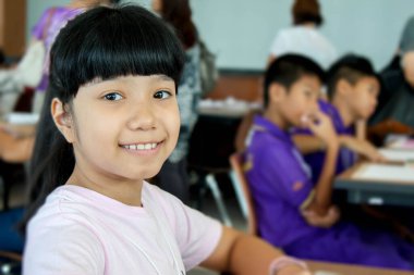 Mutlu Asyalı çocuk sınıfta gülümsüyor.