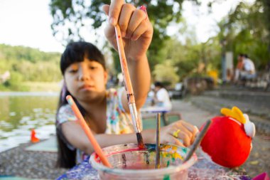 Parkta resim yapmak için boya fırçası toplayan Asyalı kız.