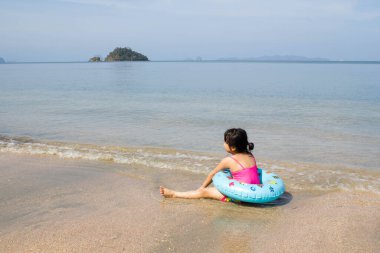 Yüzme yüzüklü Asyalı kız Pakistan, Trang, Tayland plajında oynuyor.