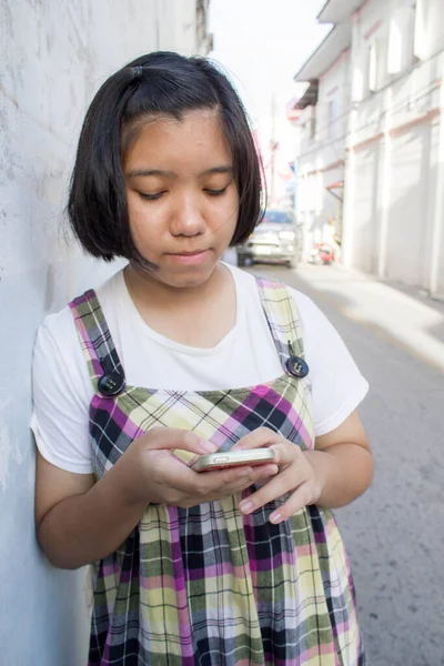 亚洲女孩用智能手机靠在墙上 — 图库照片