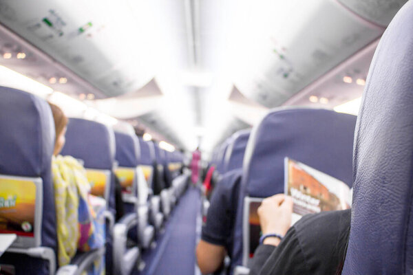 Interior of airplane with stewardess and passengers  on seats