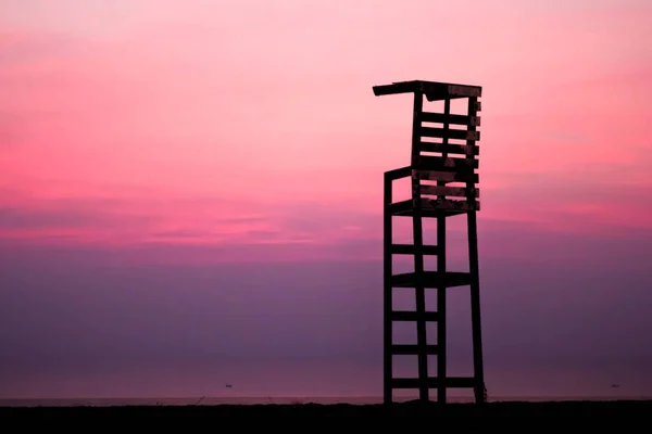 Krzesło Ratownika Plaży Abstrakcyjnym Rozmytym Tłem Czerwonego Nieba — Zdjęcie stockowe