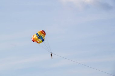 Adam mavi gökyüzü arka planında paraşütle atlıyor