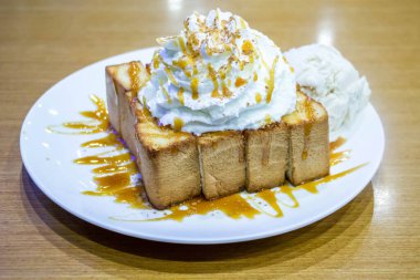 Tahta masadaki beyaz tabakta ballı tost
