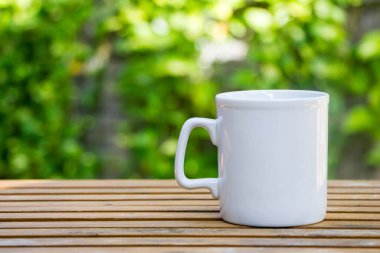 Beyaz kahve fincanı, ahşap masa üzerinde.