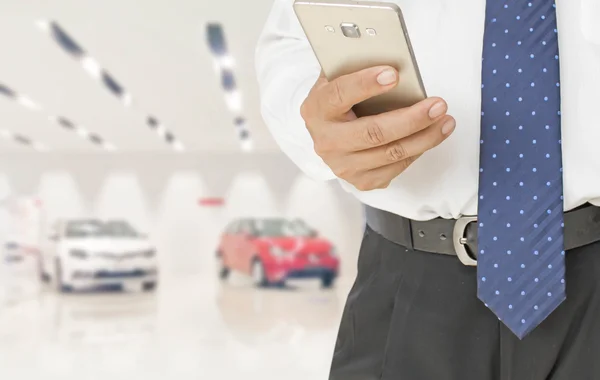 Businessman using smart phone at car showroom — Stock Photo, Image
