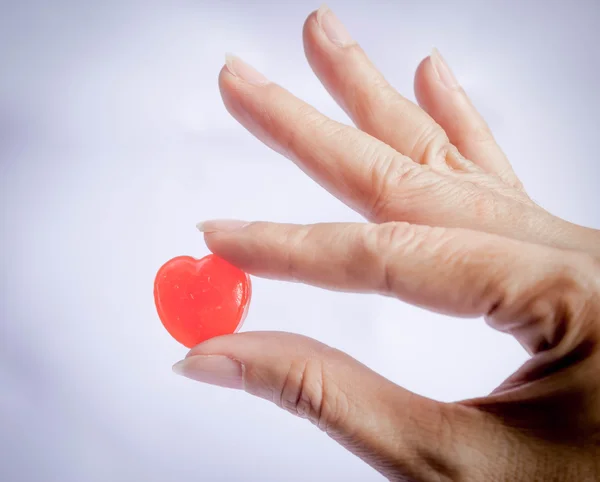Hand hålla röda hjärtat godis — Stockfoto