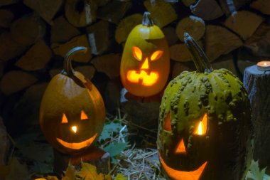 Geceleri Helovin 'de yakacak odunların arkasında parlayan üç balkabağı. Korkunç bir tatil.