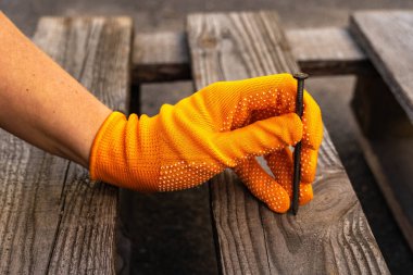 Elindeki turuncu eldivende tahta bir çivi var.