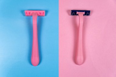 Mavi üzerine pembe bir tıraş makinesi ve pembe arka planda pembe bir tıraş makinesi. Hijyen, cilt temizliği. yakın plan
