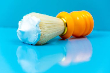 Mavi arka planda turuncu bir tıraş fırçasında tıraş köpüğü. Cilt bakımı