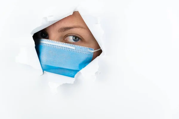 Женщина Медицинской Маске Смотрит Через Дыру Белой Бумажной Стене Боязнь — стоковое фото