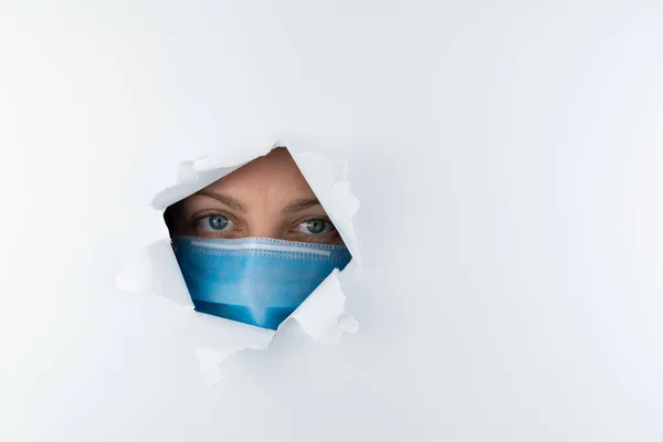 Женщина Медицинской Маске Смотрит Через Дыру Белой Бумаге Боязнь Коронавируса — стоковое фото