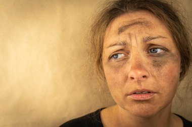 Kahverengi arka planda evsiz bir kızın üzgün yüzünün yakın çekimi. Metin için boş alan