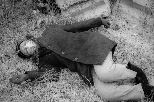 医療マスクのホームレスの男がぬれた地面に無意識のうちに横たわっている その汚れた男は地面の上に死んでいる 白黒写真 — ストック写真