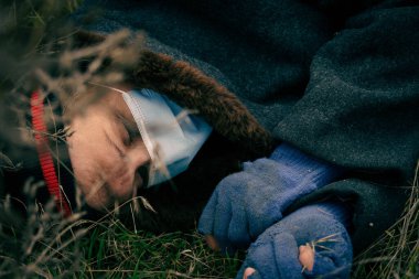 Zavallı pis adam yerde ölü yatıyor. Tıbbi maskeli evsiz bir adam ıslak zeminde bilinçsiz bir şekilde yatıyor.