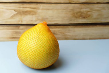 Pomelo mavi bir arka planda plastik bir ağa sarılı. Metin yazmak için boş alan