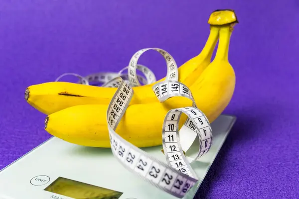 Skali Elektronicznej Dwa Banany Taśma Pomiarowa Fioletowym Tle Zdrowy Styl — Zdjęcie stockowe