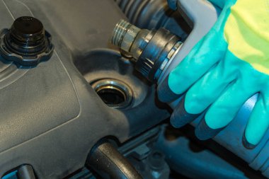 Eldivenli eller gri yağ tenekesini araba motorunun üzerinde tutar. Araba tamiri ve bakım konsepti.