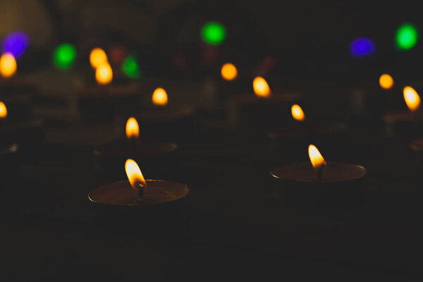 Many burning candles and colorful lanterns on a wooden background, shot with shallow depth of field