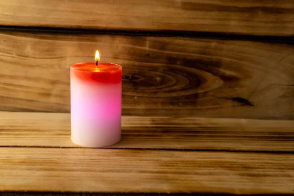 Candle on a wooden background. A red and white candle that changes color when you light it .Shallow depth of field. Christmas miracle