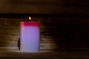 Ahşap bir arka planda mum. Yaktığınızda renk değiştiren kırmızı ve beyaz bir mum. Yüzeyin sığ derinliği. Noel mucizesi