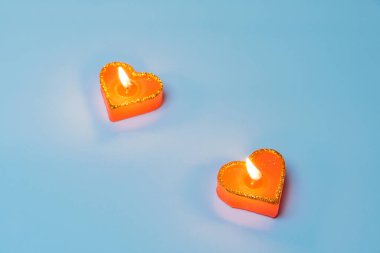 Mavi arka planda kalp şeklinde yanan kırmızı mumlar. Aşkın sembolü. Sevgililer Günü. Randevu kavramı, romantizm..