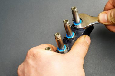 İngiliz anahtarıyla bir adamın eli arabanın gaz tüpünü söküyor. Araç gaz teçhizatının bakımı ve onarımı