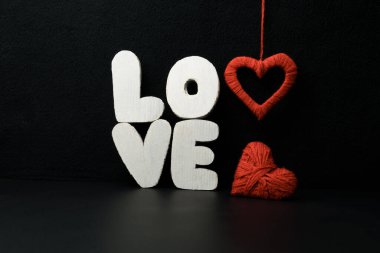 Tahta harfler aşk yazar ve siyah arka planda iki kalp. Sevgililer Günü, romantizm ve aşk