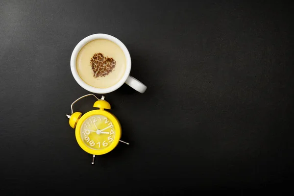 Tasse Cappuccino Und Wecker Über Schwarzem Hintergrund Mit Kopierraum Schokoladenherz — Stockfoto