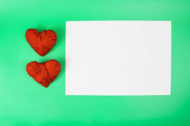 Kopya alanla sevgililer günü konsepti çok güzel. İki kırmızı kalp ve yeşil arkaplana yazı yazmak için beyaz bir sayfa..
