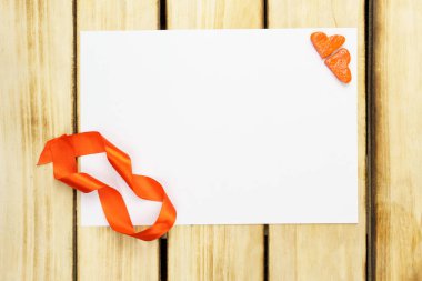 Tebrik kartı, beyaz boş kağıt, kırmızı kurdele ve tahta arka planda kalp şeklinde zencefilli kurabiye. Sevgililer günü kartı, düz yatak, üst manzara.