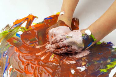 Çocukların elleri beyaz bir arka plana boya sürüyor. Çocuk elleriyle çiziyor.