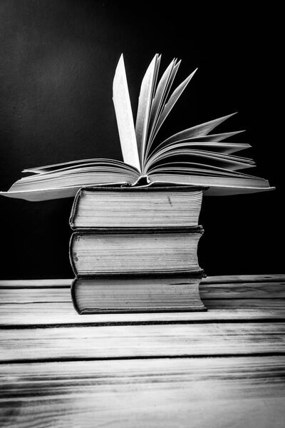 A stack of books on the table. At the top is an open book. World book day concept. Black and white photo