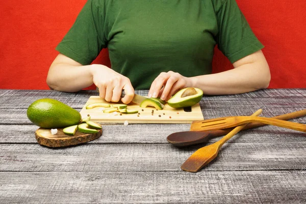 Healthy food preparation process. The girl cuts an avocado with a knife. Healthy food concept