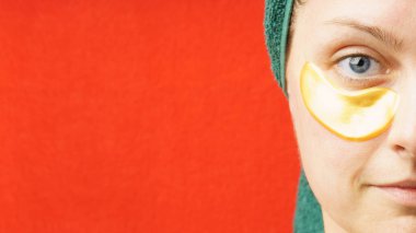 Gözlerinin altında yamalar olan bir kadın. Cilt bakımı konsepti, yaşlanmayı önleyen nemlendirici göz maskesi, altın hidrojel bantlar. Kopyalama alanı olan yarım yüz portresi