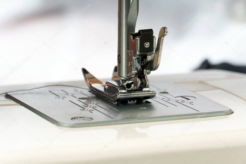 close-up of the sewing machine foot. Needle plate, foot and feed of the sewing machine. clothing industry