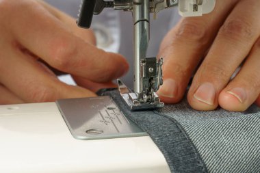 the process of shortening jeans pants on a sewing machine clipart