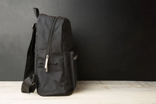 Mochila Fundo Parede Preta Uma Mesa Madeira Branca Com Espaço — Fotografia de Stock