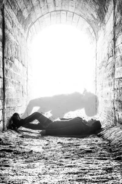the soul leaves the body after the death of a woman. death of a woman in a tunnel. death concept, light at the end of the tunnel. black and white photo with grainy effect