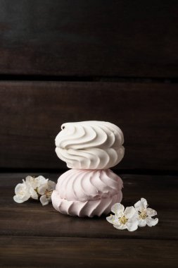 Şekerleme. Birbiri üzerine iki yuvarlak krema. Koyu ahşap arka planda beyaz çiçeklerle süslenmiş. Fotokopi aletiyle.