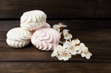 Şekerleme. Koyu ahşap arka planda beyaz bir çiçekle süslenmiş krema. yakın plan