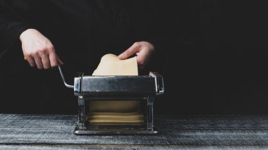 Hamuru koyu bir ahşap arka planda makarna makinesine dök.