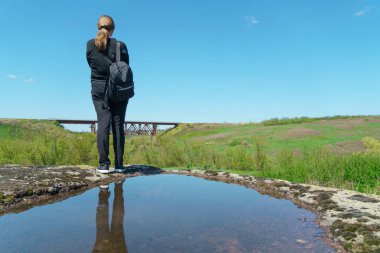 Sırt çantalı bir kadın uçurumun kenarında durur, kız güzel yerlere seyahat eder, hedefe ulaşır. Güzel manzara.