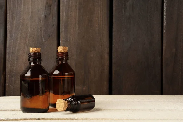 cosmetic glass bottle with cork stopper. brown bottles on white table against dark wood wall