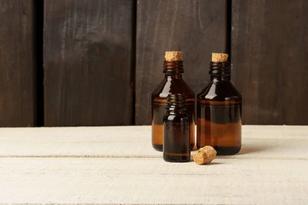cosmetic glass bottle with cork stopper. brown bottles on white table against dark wood wall