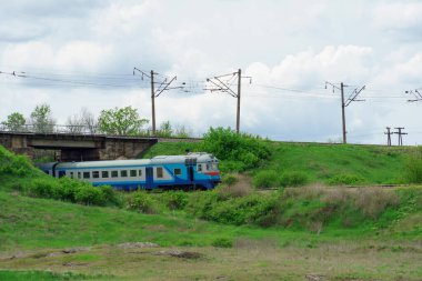 Dizel tren. Mavi yolcu treni çimlerin üzerinde bir rayda gidiyor. Tarlada demiryolu.