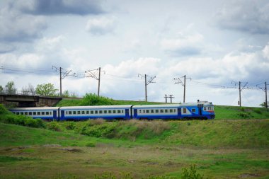 Dizel tren. Mavi yolcu treni çimlerin üzerinde bir rayda gidiyor. Tarlada demiryolu.