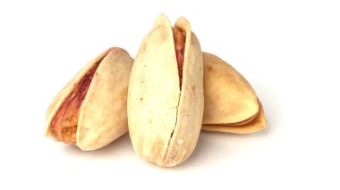 Beyaz arka planda üç fıstık var. Kızarmış şam fıstığı..